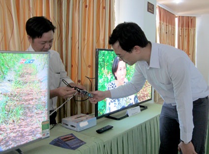 Anh Lê Mỹ Nhãn, Cán bộ Trung tâm Văn hóa - Học tập cộng đồng xã Long Sơn, TP. Vũng Tàu (trái) tìm hiểu về thiết bị set - top - box hỗ trợ cho các tivi công nghệ cũ nhận được tín hiệu của truyền hình số mặt đất.